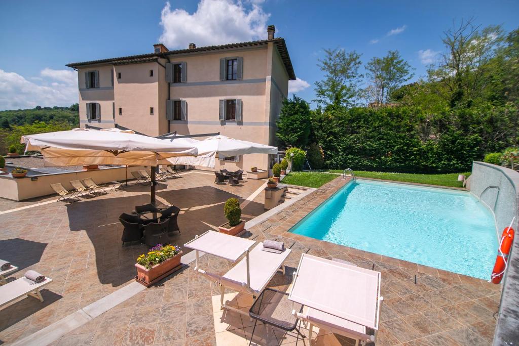 a house with a swimming pool with chairs and an umbrella at Hotel La Colonna in Siena