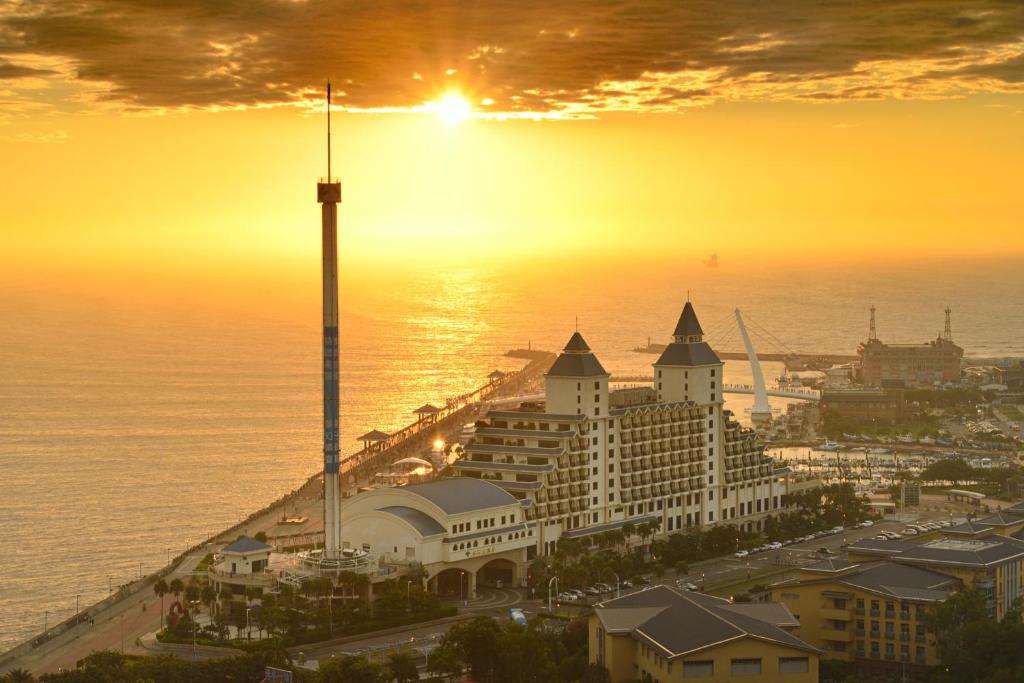 a view of a resort with the sun setting over the ocean at Fullon Hotel Tamsui Fishermen's Wharf in Tamsui