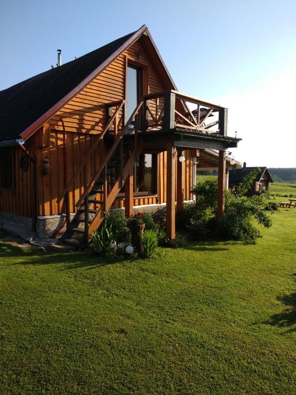 une grande cabine en bois avec une grande terrasse sur un champ dans l'établissement Žalioji, à Paduyelis