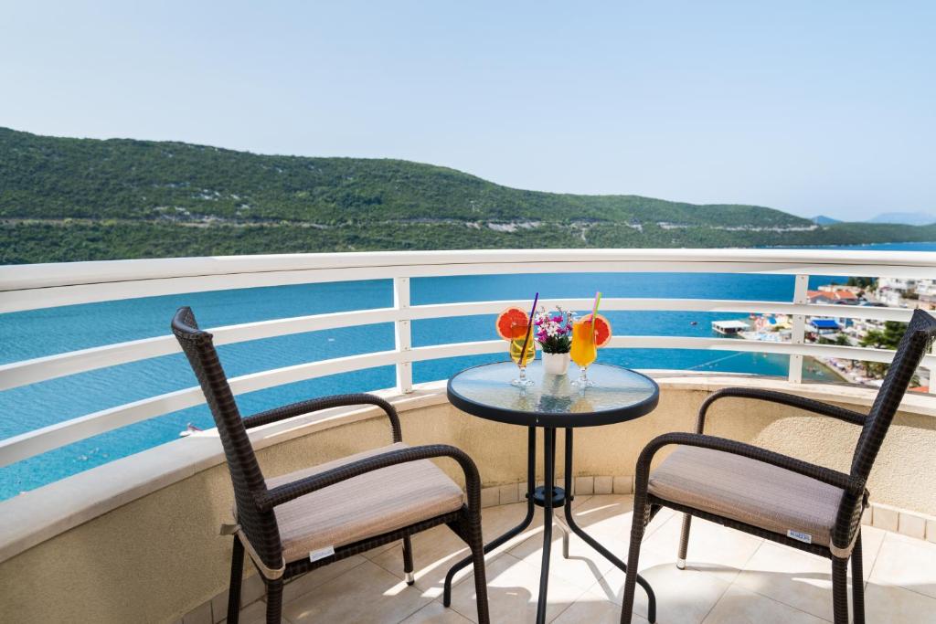 a table with two chairs and a vase of flowers on a cruise ship at Hotel Agava in Neum