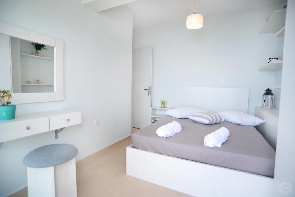 a white bedroom with a bed with two pillows at MOUSELIS APARTMENTS in Kalymnos