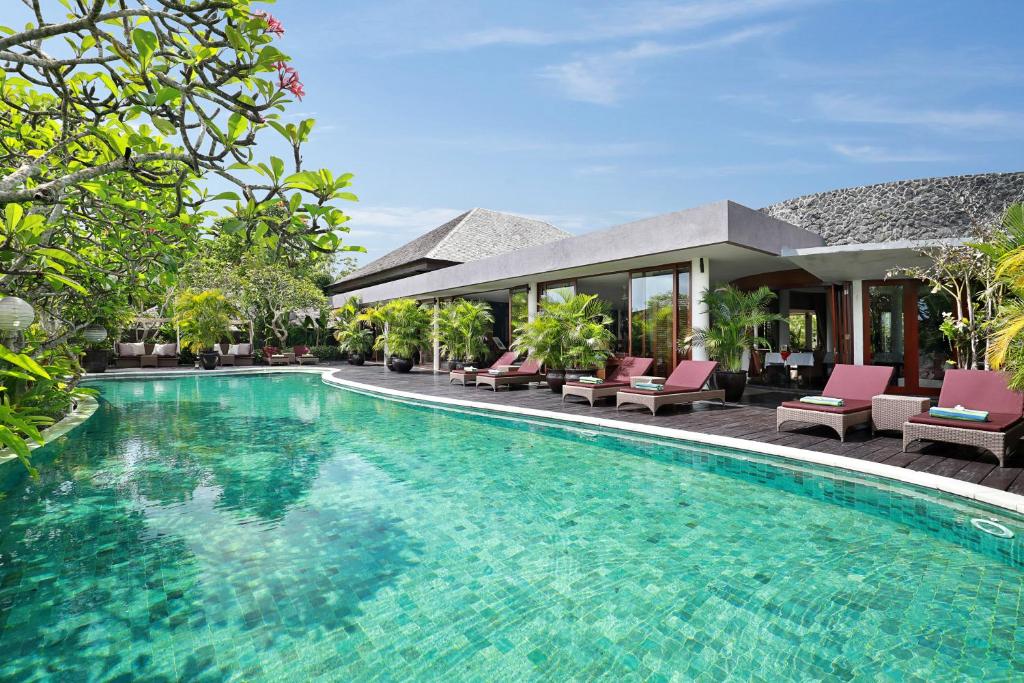 a swimming pool in front of a villa at Gending Kedis Luxury Villas & Spa Estate in Jimbaran