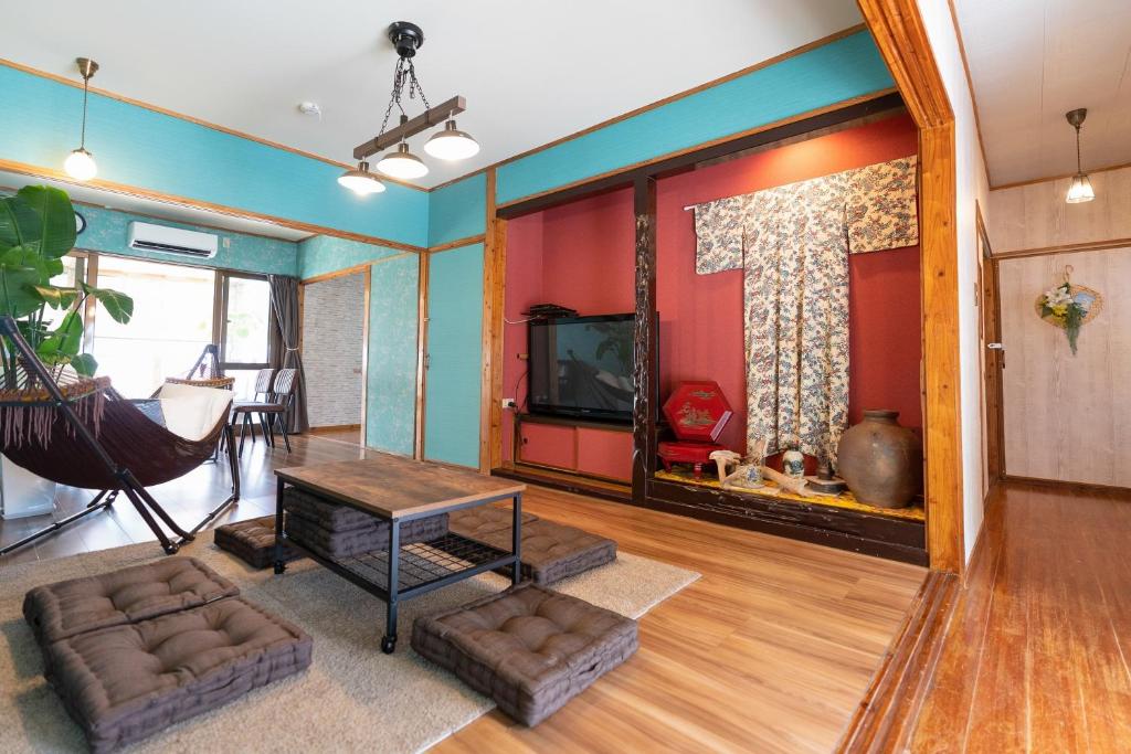 uma sala de estar com uma televisão e uma mesa em 沖縄古民家お宿ななつぼし Okinawa Traditional House Nanatsuboshi em Naha