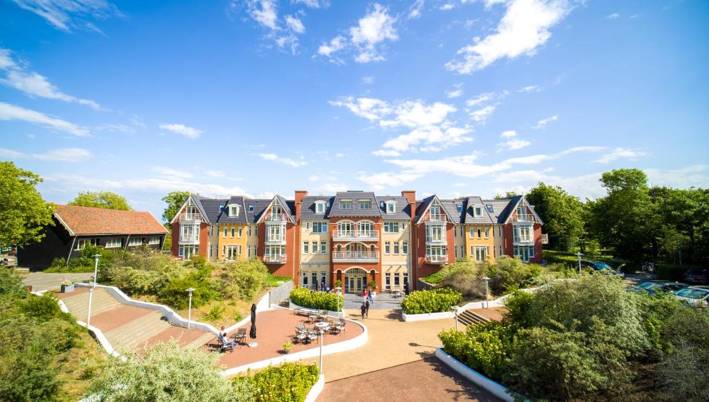 un grand bâtiment avec un parc en face dans l'établissement Grand Hotel Ter Duin, à Burgh-Haamstede