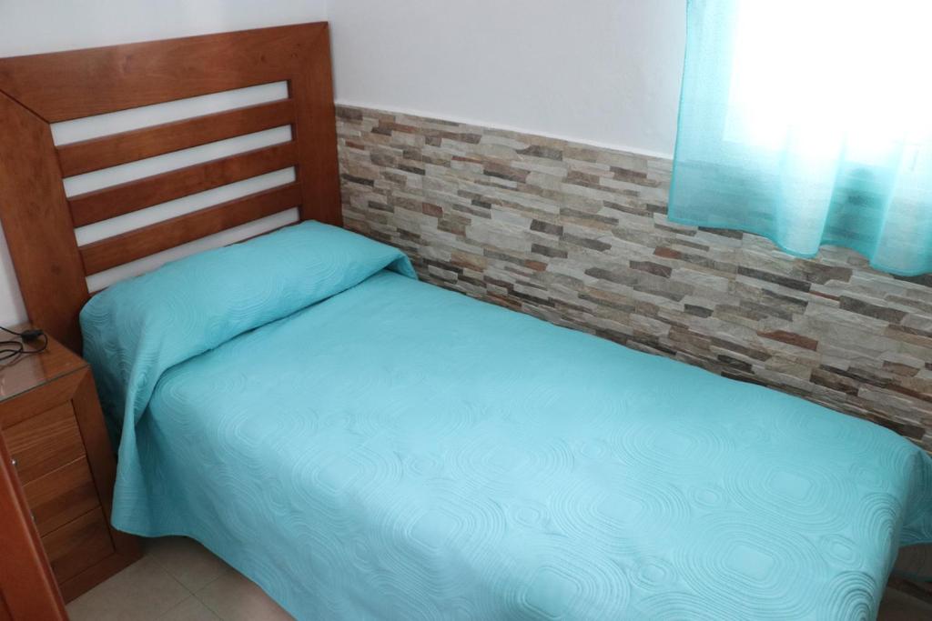2 łóżka pojedyncze w sypialni z ceglaną ścianą w obiekcie Apartamento para 3 en el centro w mieście Conil de la Frontera