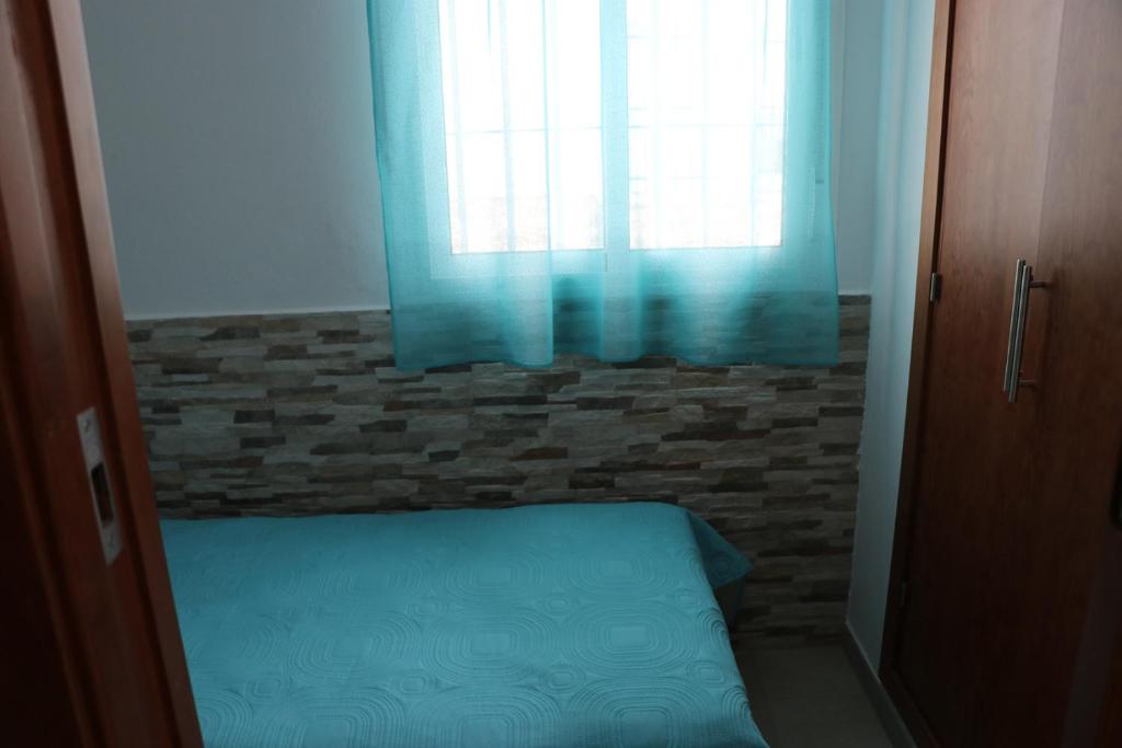 sypialnia z łóżkiem i oknem z niebieskimi zasłonami w obiekcie Apartamento para 3 en el centro w mieście Conil de la Frontera