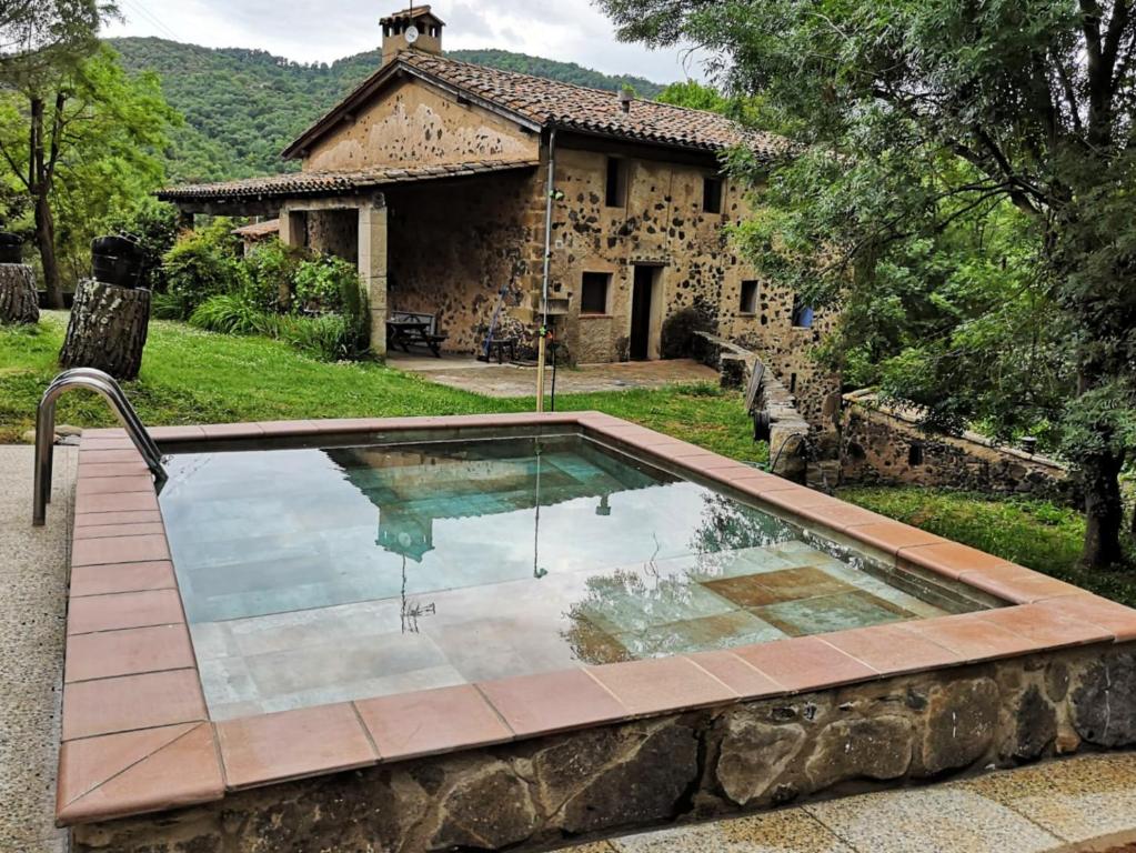 a swimming pool in front of a stone house at Mas Violella allotjament rural in Sant Joan les Fonts