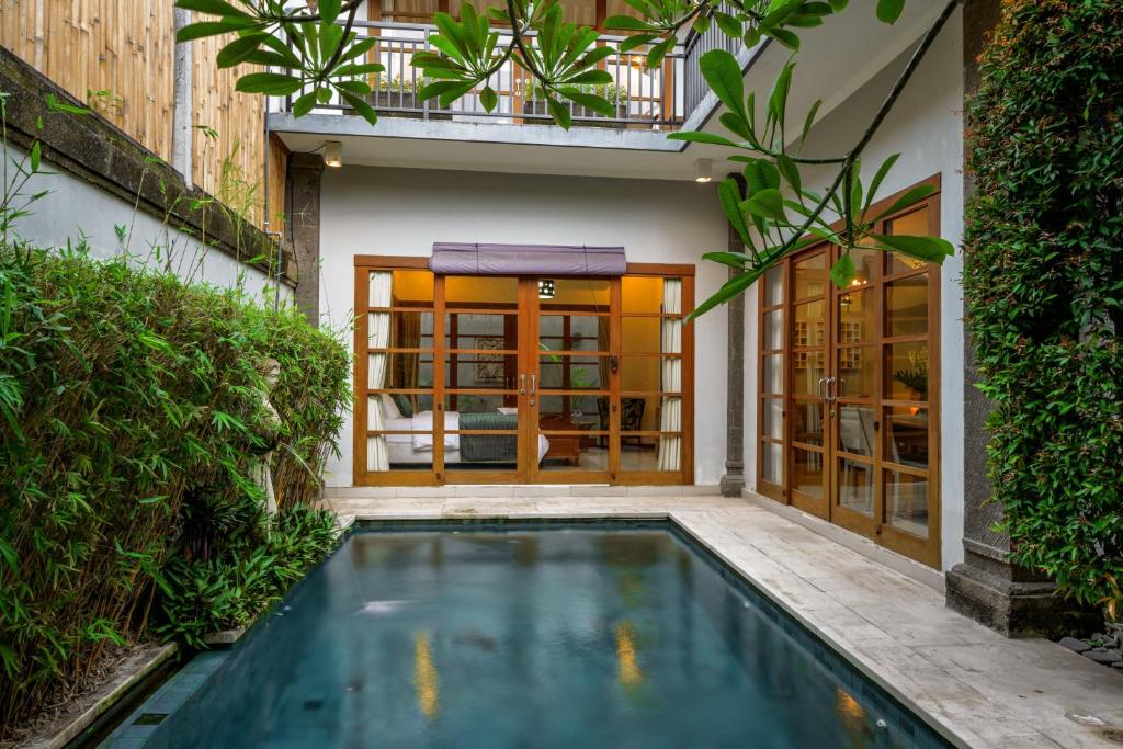 a swimming pool in front of a house with a building at Sonti Villa in Seminyak
