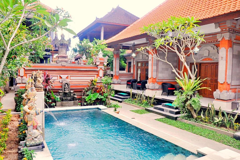a house with a swimming pool in front of a house at Nick's Homestay in Ubud