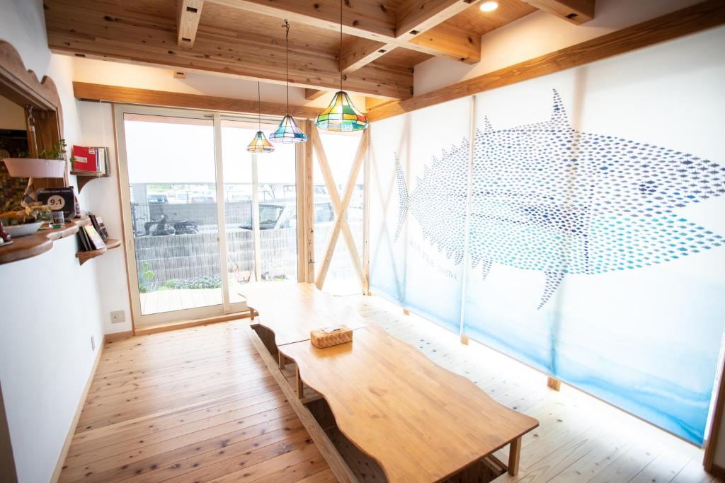 een woonkamer met een tafel en een groot raam bij Katsuo Guest House in Kochi