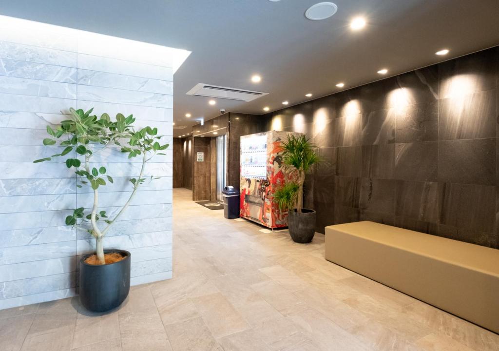 a lobby with a bench and potted plants at Sonezaki Luxe Hotel in Osaka