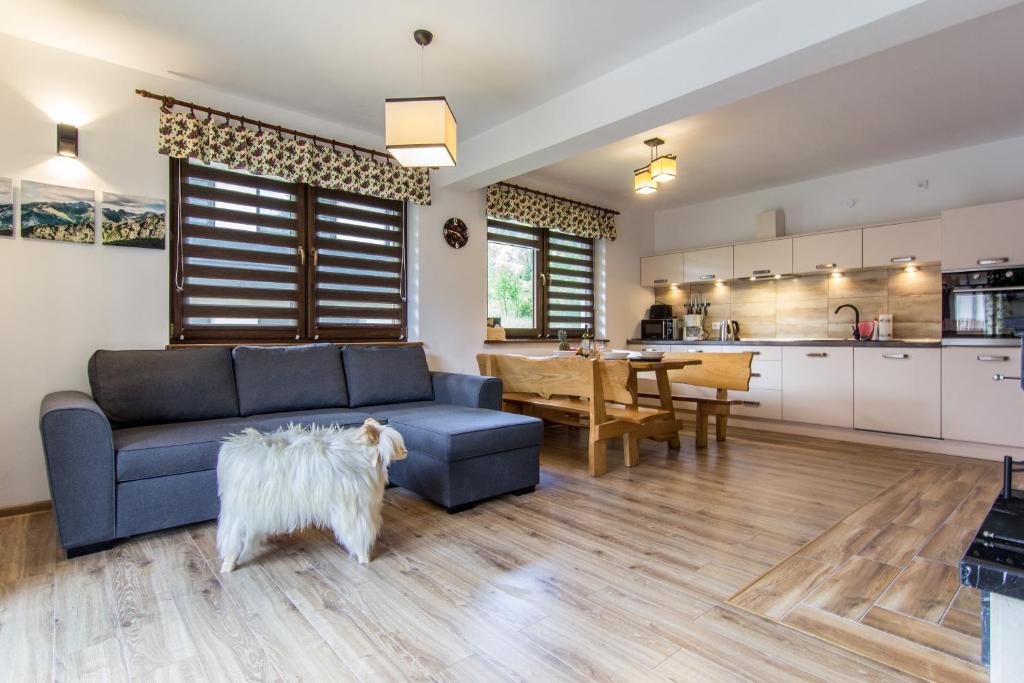 a living room with a blue couch and a kitchen at Domki Czajki Zakopane in Kościelisko