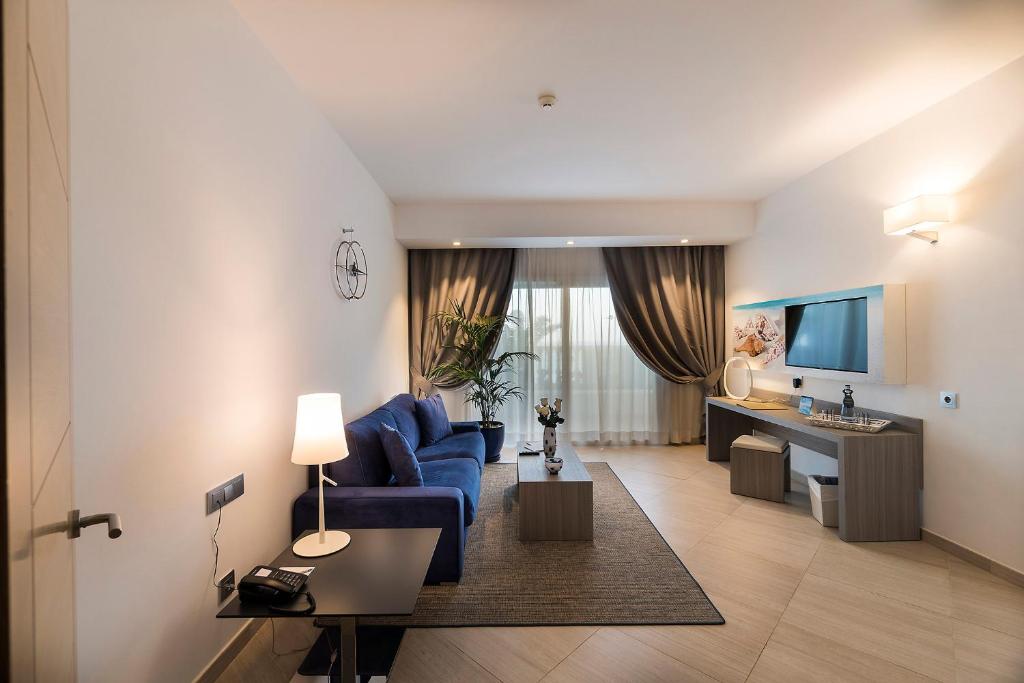 a living room with a blue couch and a kitchen at Royal Palm Resort & Spa - Adults Only in Playa Jandia