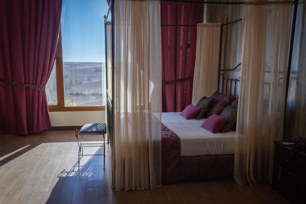 um quarto com uma cama e uma grande janela em Complejo Enoturístico Finca La Estacada em Tarancón