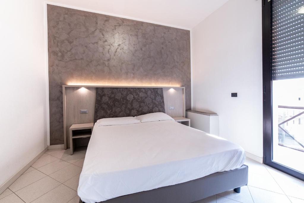 Un dormitorio con una gran cama blanca y una ventana en Residenza Sol Holiday, en Rímini