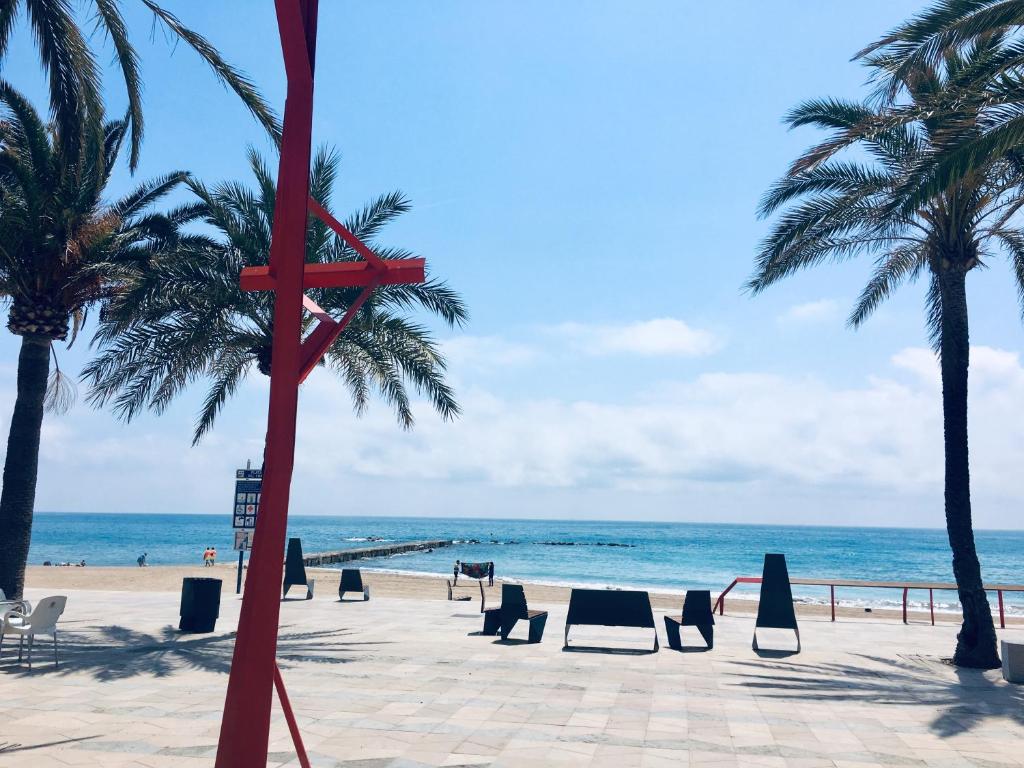 a red cross on a beach with palm trees and the ocean at ViNALUX in Vinaròs