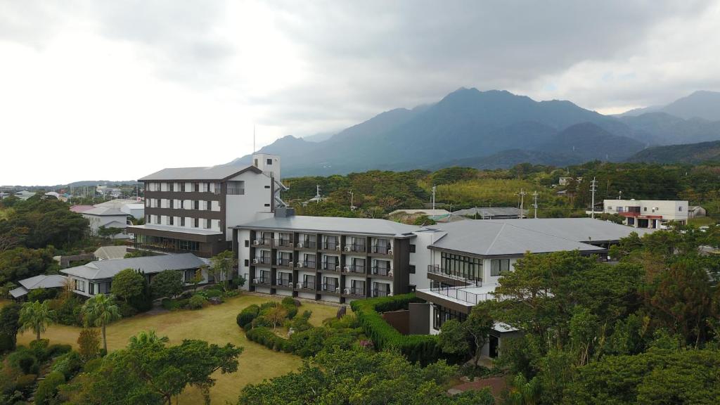 eine Luftansicht eines Gebäudes mit Bergen im Hintergrund in der Unterkunft Yakushima Green Hotel in Yakushima