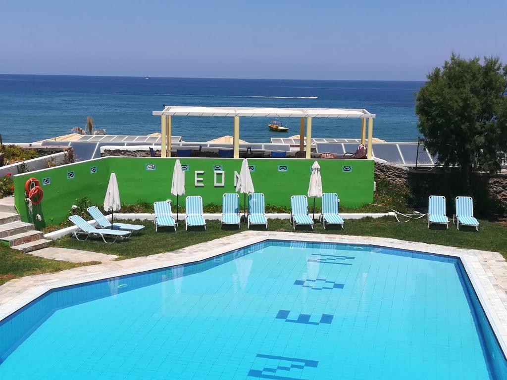 basen z krzesłami i ocean w tle w obiekcie Neon Hotel w mieście Stalida