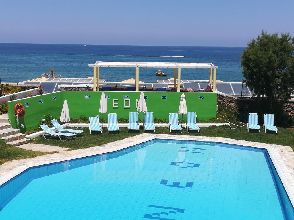 a swimming pool with chairs and the ocean in the background at Neon Hotel in Stalís