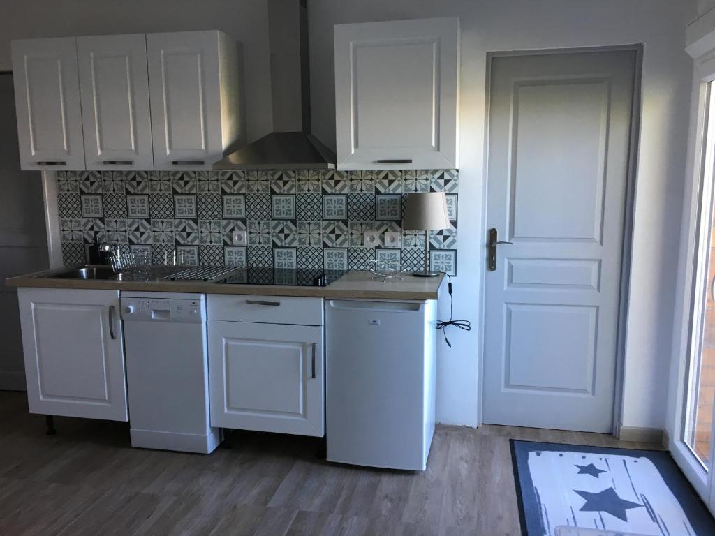 uma cozinha com electrodomésticos brancos e uma porta branca em agréableT2 em Soustons