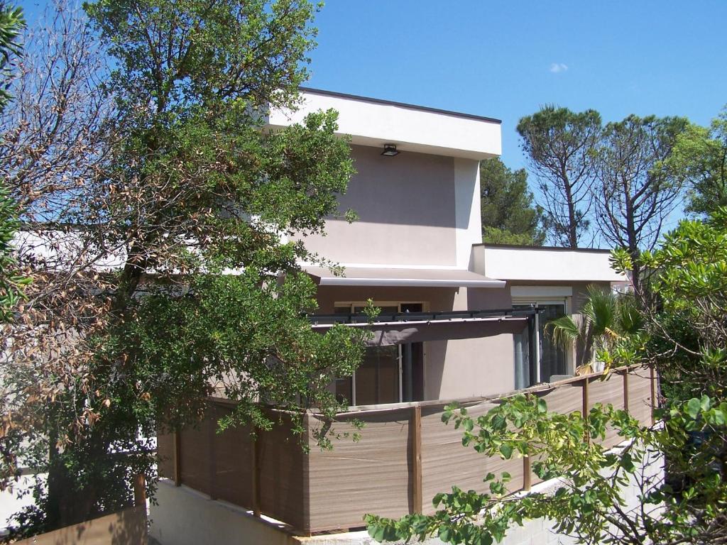 une maison blanche avec des arbres devant dans l'établissement Villa Némausa / Saint-Aygulf, à Saint-Aygulf