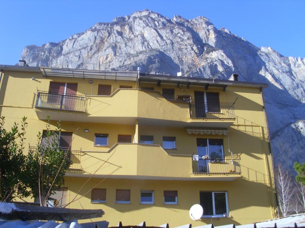 a yellow building with a mountain in the background at PIETRAMURATA APPARTAMENTO VISTA MONTAGNA terzo piano in Dro
