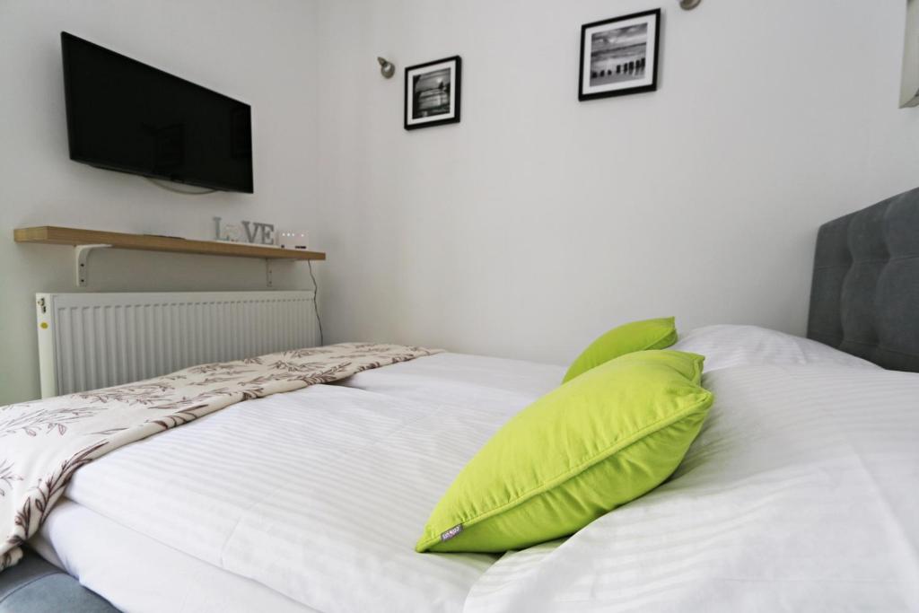 a white bed with two green pillows on it at Villa Juliette by Baltic Home in Świnoujście