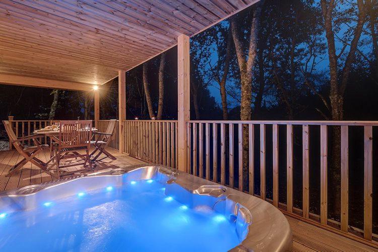 a jacuzzi tub on a deck with a table at Willow Lodge, South View Lodges, Exeter in Exeter