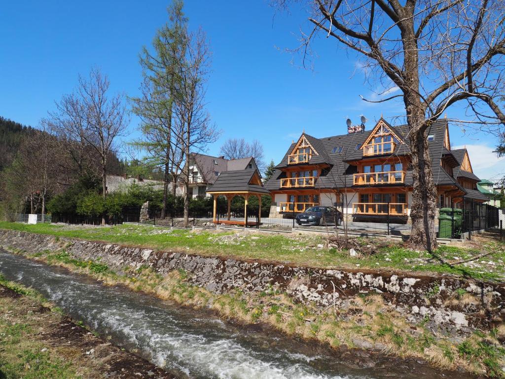 a large house with a river in front of it at VIP Apartamenty FOLK RESIDENCE in Zakopane