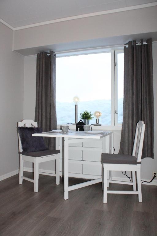 a white desk and two chairs in a room with a window at Studioleilighet i Haukedalen in Holsen