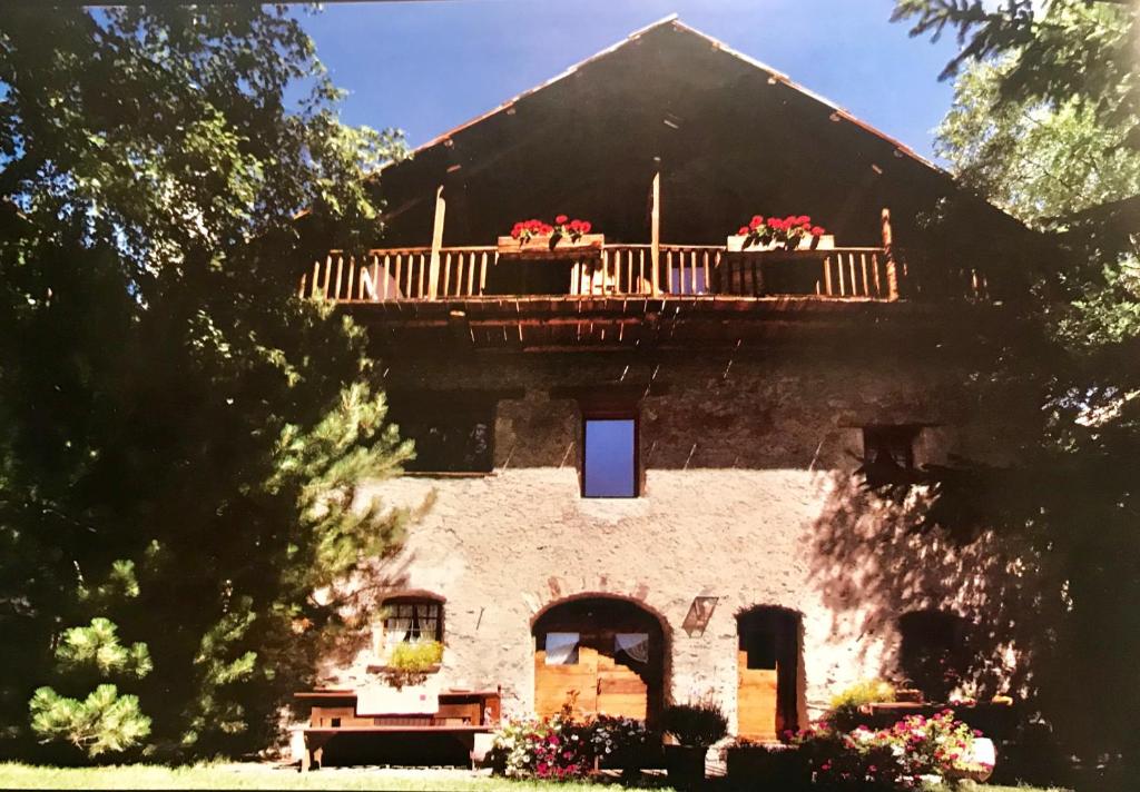 an old house with a balcony with flowers on it at Casa Sestrieres Chalet Vialattea in Sauze di Cesana