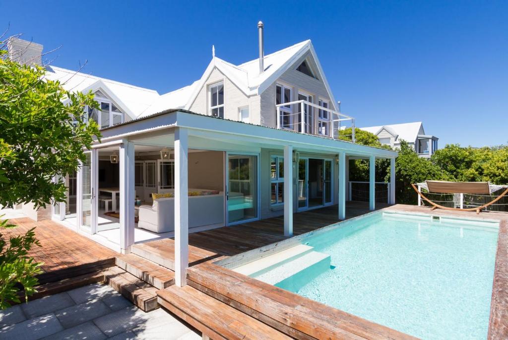 a house with a swimming pool in front of a house at Fin Whale Beach House in Kommetjie