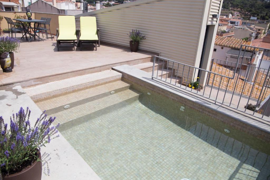 a swimming pool on top of a building with chairs at Bel's Home in Sant Feliu de Guixols