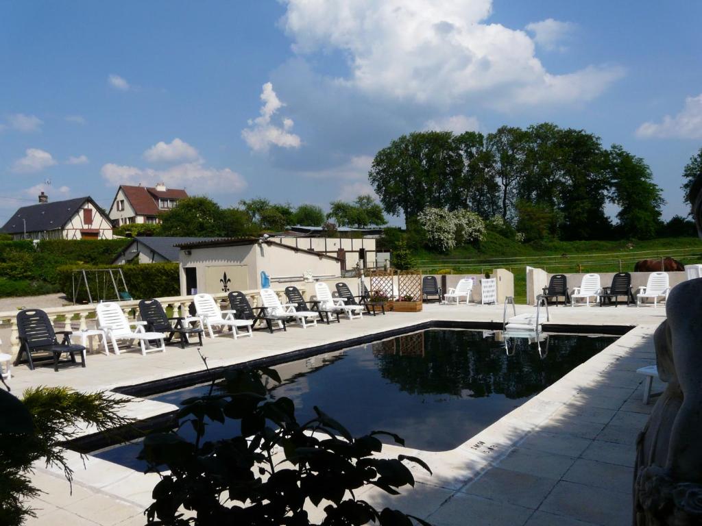uma piscina com cadeiras brancas e cadeiras ao redor em Gîte du Domaine de La Reine Blanche em Criquetot-sur-Longueville