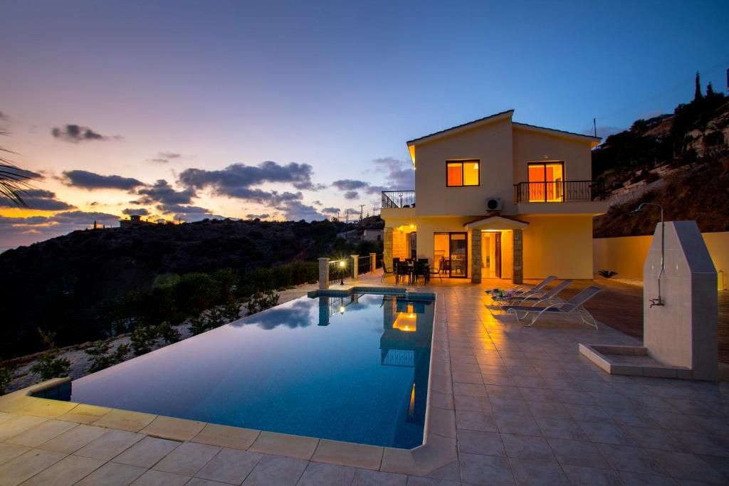 a villa with a swimming pool in front of a house at Villa Blue Jadeite in Peyia