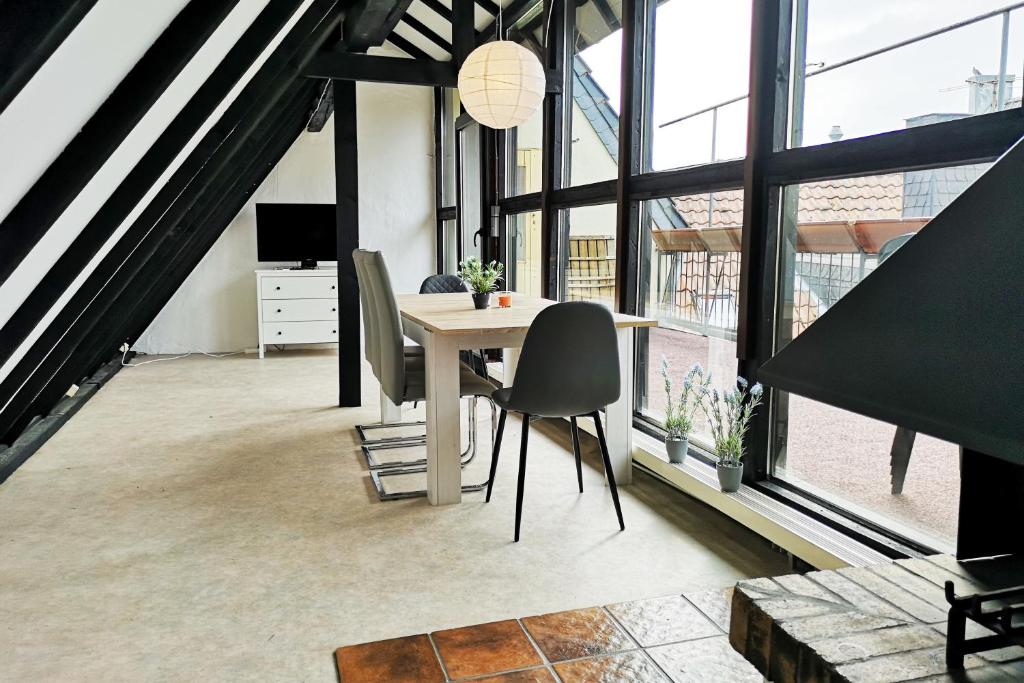 ein Esszimmer mit einem Tisch, Stühlen und Fenstern in der Unterkunft Zentrales Apartment mit Dachterrasse in Goch
