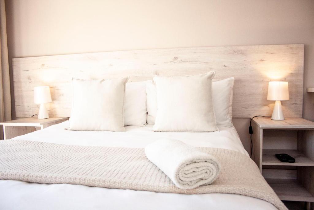 1 dormitorio con 1 cama blanca con almohadas y 2 lámparas en Kelzane Self-Catering, en Gonubie