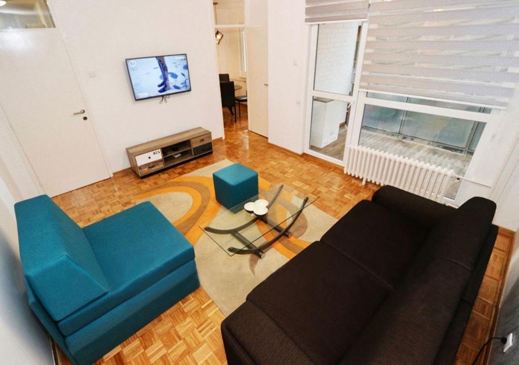 ein Wohnzimmer mit einem Sofa, einem Tisch und einem TV in der Unterkunft Apartment Delta Sava New Belgrade in Belgrad