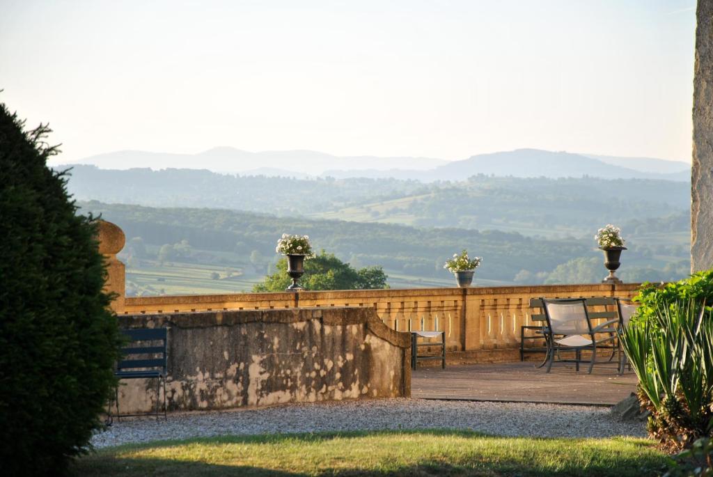 a patio with chairs and a fence with mountains in the background at Chateau De Martigny in Poisson