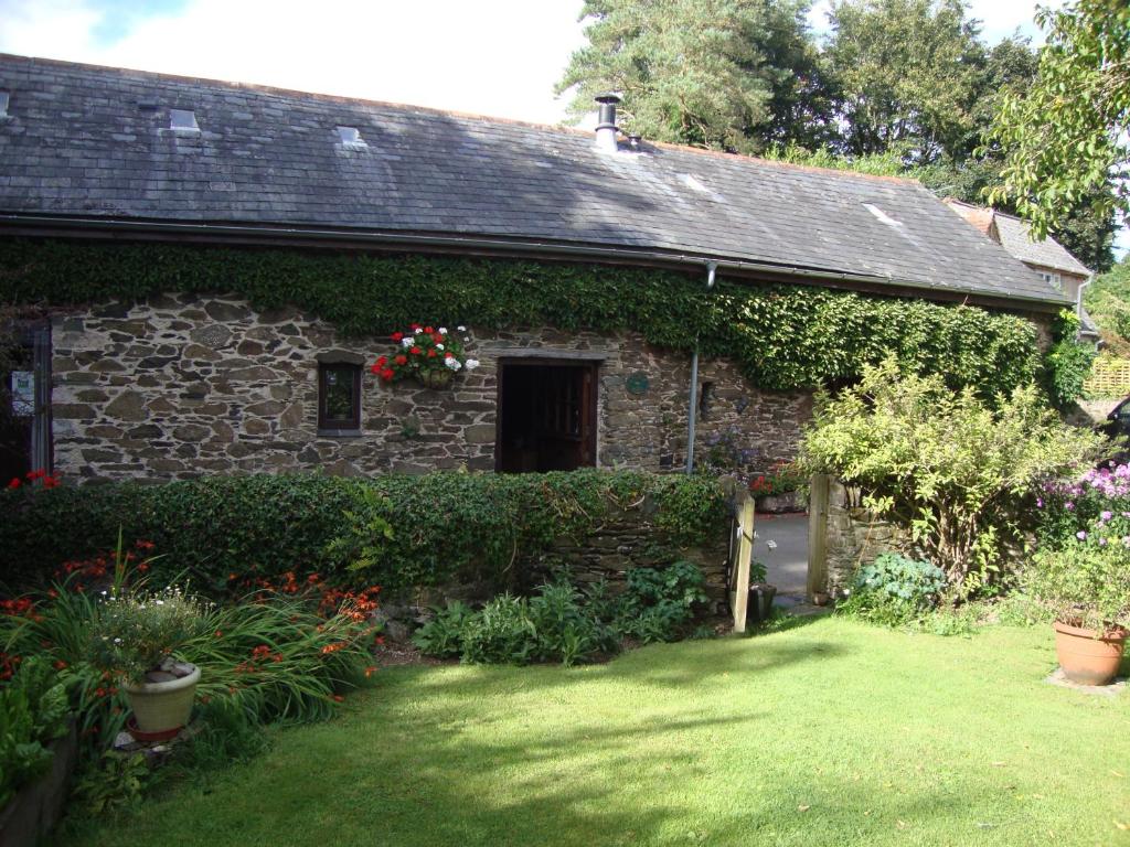 an old stone house with a garden and flowers at Church Barn in Harberton