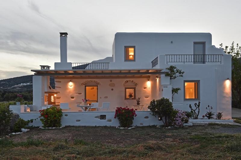 a large white house with a sunset behind it at Tonia Apartments Paros in Chrissi Akti