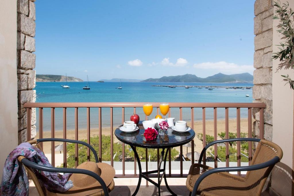 a table with two glasses on a balcony with the ocean at Methoni Beach Hotel in Methoni