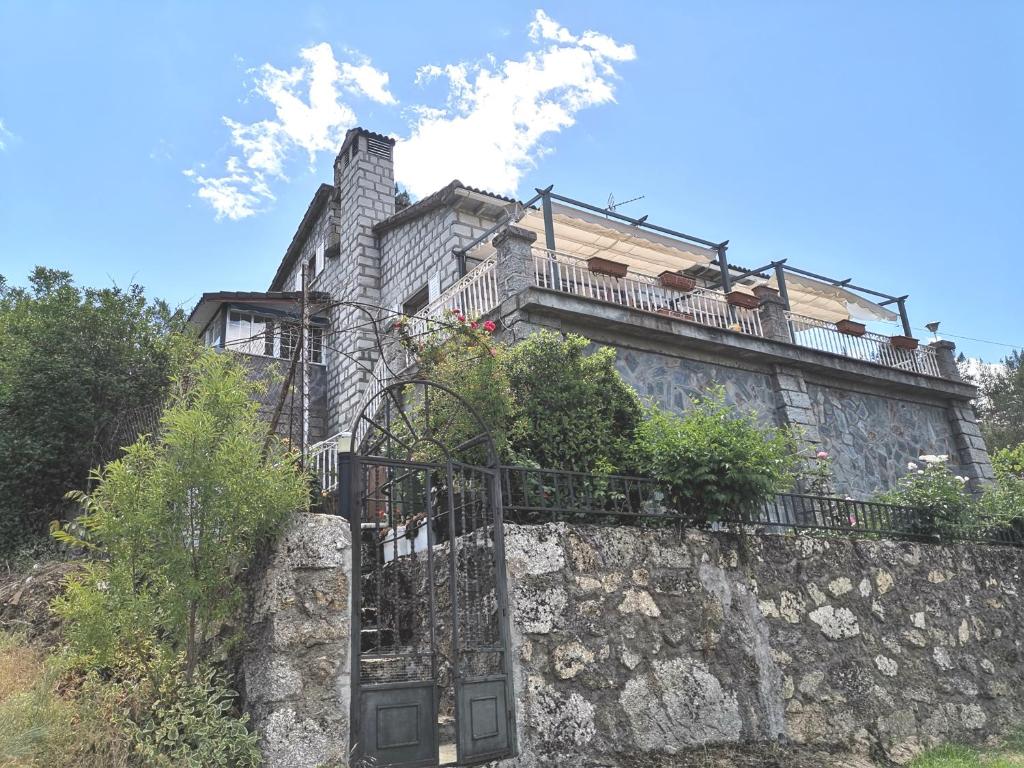 une maison au-dessus d'un mur en pierre dans l'établissement Los corzos, à Burgohondo