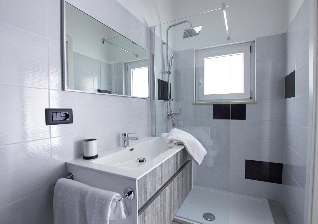 uma casa de banho branca com um lavatório e um espelho em B&B Alto Salento - Pool and Sun em Pulsano