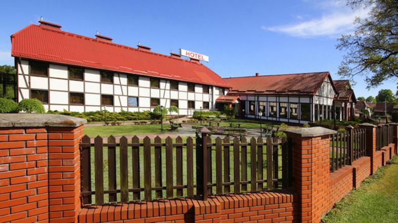una valla de ladrillo frente a un edificio en Hotel Taurus en Święta Lipka