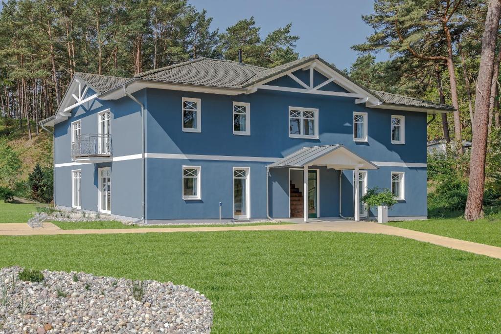 a blue house with a yard at Upstalsboom Apartments Trassenheide in Trassenheide