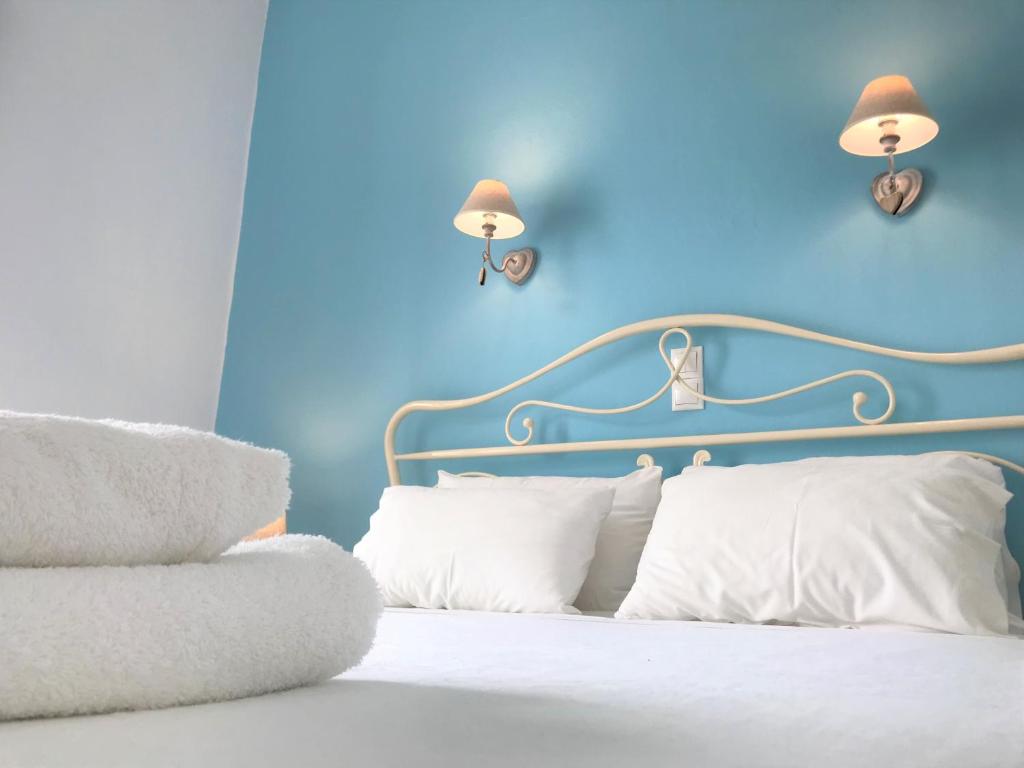 Dormitorio azul con cama con sábanas y almohadas blancas en Danaides Studios, en Batsi
