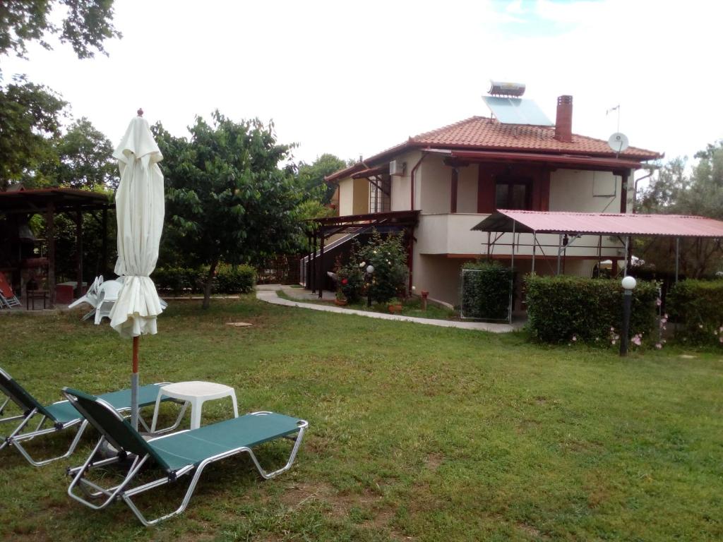 two lawn chairs and an umbrella and a house at Olympus Aegean House in Leptokarya