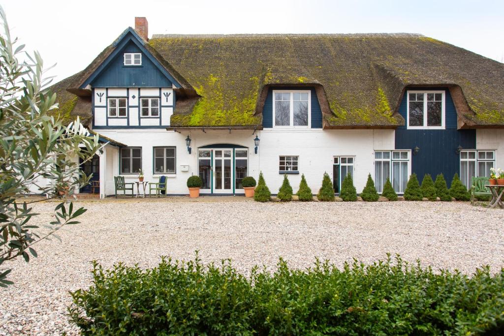 a large white house with a turf roof at Landhotel Teichwiesenhof, Bed&Breakfast in Oldenburg in Holstein