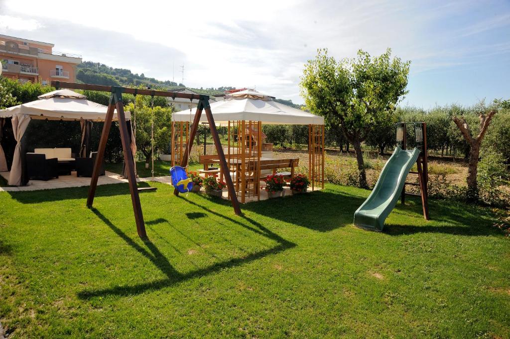 a playground with a slide and a table and an umbrella at Hotel Lidia in Alba Adriatica